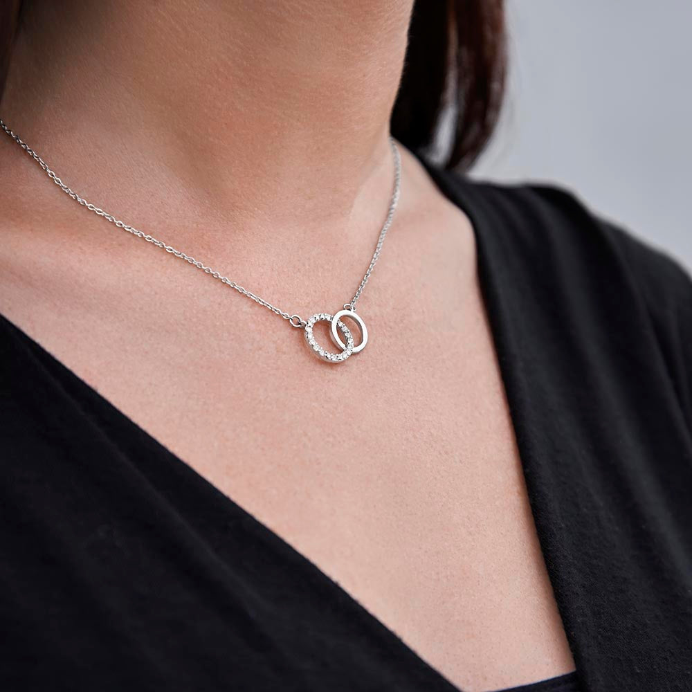 Woman wearing a Elegant Perfect Pair Necklace on a gift card, featuring a large circle dipped in 14K white gold and set with 20 dazzling cubic zirconia crystals, total pendant width of 0.8 inches, 18-inch chain with a 2-inch extension, and a parrot clasp, in a Luxury Box with an LED spotlight.