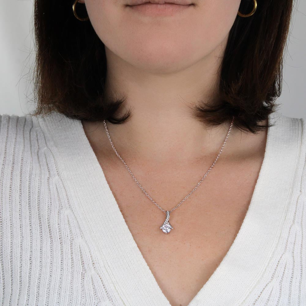 beautiful womans chest with a necklace on it. the necklace has a large cubit zirconia in the middle and is suspended on a lpiece of metal with numerous small cubity zirocnia on it