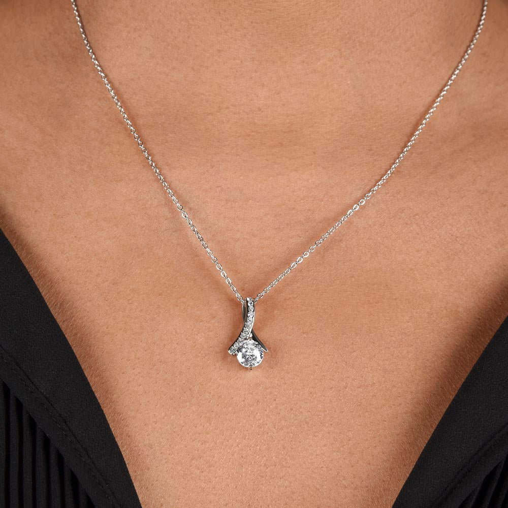 beautiful womans chest with a necklace on it. the necklace has a large cubit zirconia in the middle and is suspended on a lpiece of metal with numerous small cubity zirocnia on it