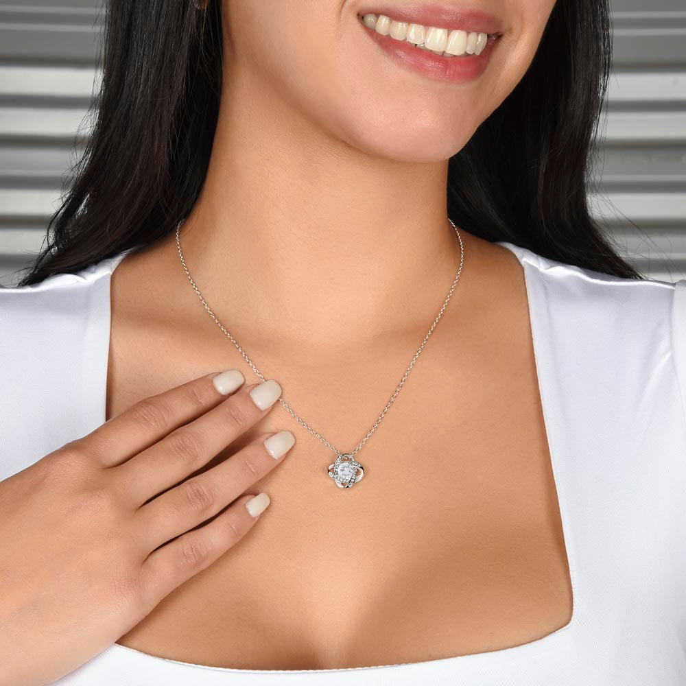woman wearing a 14k white gold over stainless steel love knot necklace, featuring a 6mm round cut cubic zirconia stone and adjustable chain length of 18 to 22 inches."
