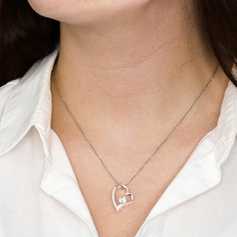 a womans chest with a stainless steel heart shapped pedant necklace with a large cz diamond and small ca chip diamonds on the perimeter